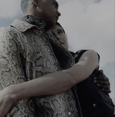 a man and woman embracing each other in front of the sky