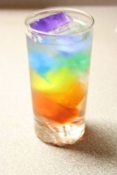 a rainbow colored drink in a glass on a table