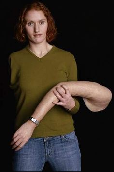 a woman with red hair wearing a green shirt and blue jeans is posing for the camera