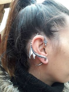 a close up of a person with ear piercings on their ears and behind them is a woman's head