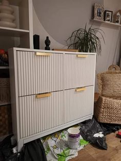 a white cabinet sitting on top of a hard wood floor next to a wicker chair