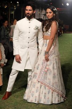 a man and woman standing next to each other in front of a crowd at a fashion show