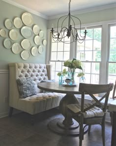 a dining room table and chairs with plates on the wall behind it, along with a bench