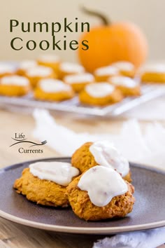 pumpkin cookies on a plate with white icing and an orange in the back ground