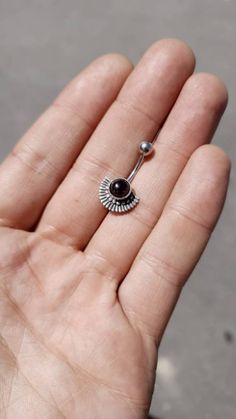 a person's hand holding a tiny black and white nose ring