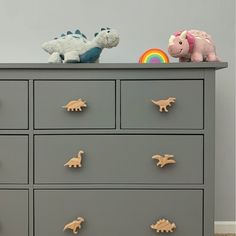 a grey dresser with toy dinosaurs on top