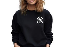 a woman wearing a new york yankees black sweatshirt with white ny logo on the front