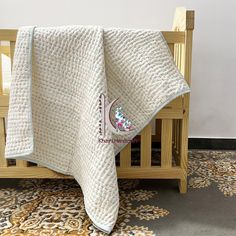 a baby crib with a white blanket on it's top and the bottom