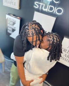 two women hugging each other in front of a sign that says studio on the wall