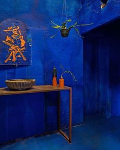 a blue room with a table and vases