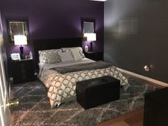 a bedroom with purple walls and a bed in the middle is lit by two lamps