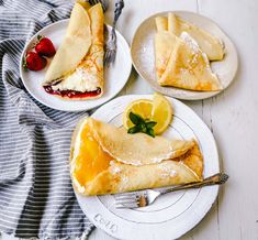 three plates filled with crepes and fruit on top of a white wooden table