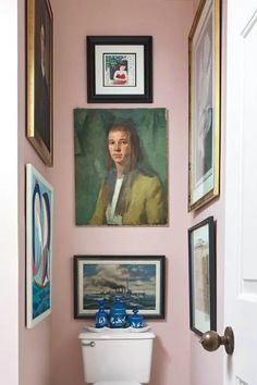 a white toilet sitting in a bathroom next to pictures on the wall and framed above it