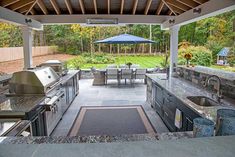 an outdoor kitchen with grill, sink and table