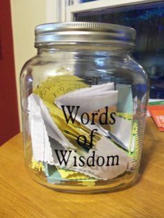 a glass jar filled with lots of paper on top of a wooden table next to a window