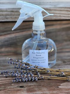 a bottle of lavender essential oil next to some lavender flowers on a wooden table with a label that says all natural room fresheners