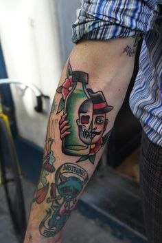 a man with a tattoo on his arm holding a beer bottle in his right hand