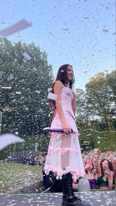 a woman in a pink dress and black boots on stage with confetti