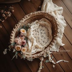 a basket filled with flowers sitting on top of a wooden floor next to a blanket