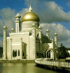 a large white building with a golden dome on it's roof next to the water