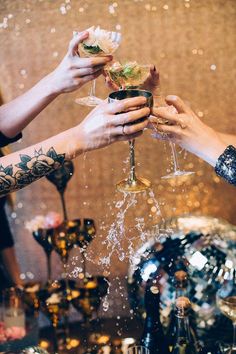 three people are toasting with drinks and confetti