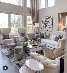 a living room filled with lots of furniture next to large window covered in curtains and chandelier