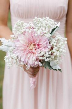 a bridesmaid holding a pink and white bouquet with baby's breath in it