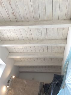 an unfinished ceiling with white paint and wood planks