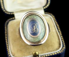 This beautiful antique Georgian era, late 18th century mourning ring is truly a beautifully crafted piece. It features a beautiful large oval face housing a lock of plaited dark blonde hair bordering a cobalt blue enamel plaque with applied rose gold lettering with the initial B. The slightly domed glazing encloses this and is original to the ring, the reverse of the face has a closed back setting and is engraved with an inscription for the departed; William Bridge, Ob 4th Mar 1797 Ae 81. The ring has chunky gold shoulders, yellow gold with warm rosey tones and a closed back setting.  It comes in an antique leather bound ring box.  A true beauty, this would be a fantastic gift for the collector of mourning jewellery or as a gift to yourself. Dated 18th century Georgian pieces are always in Antique Engraved Yellow Gold Enamel Ring, Victorian Hallmarked Oval Enamel Ring, Victorian Oval Hallmarked Enamel Ring, Antique Oval Enamel Ring Collectible, Victorian Oval Enamel Ring For Anniversary, Victorian Oval Yellow Gold Enamel Ring, Heirloom Oval Engraved Enamel Ring, Heirloom Engraved Oval Enamel Ring, Victorian Gold Enamel Oval Ring