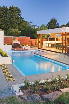 an outdoor swimming pool surrounded by landscaping