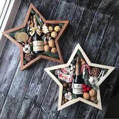 two wooden star shaped ornaments with wine bottles and nuts in them on a wood surface