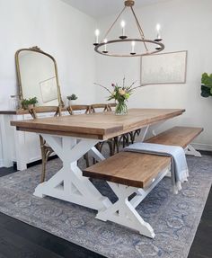 a dining room table with bench and mirror on the wall next to it in front of a rug