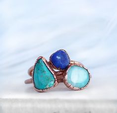 This dainty stacking ring features a tiny raw lapis lazuli stone that is electroformed with pure copper, creating a unique and organic looking setting for this beautiful July birthstone. This listing is for one lapis lazuli ring. Each ring is made by hand and electroformed for 12 hours, allowing a unique copper design to develop and encase the stone. Rings are then buffed, polished and sealed with a jeweler's wax to maximize shine and help prevent potential tarnishing and skin discoloration that Adjustable Stackable Rings With Natural Stones, Libra Stone, Clean Copper, Chrysocolla Ring, December Birthstone Ring, Copper Crystal, Raw Crystal Ring, Copper Design, Raw Stone Ring