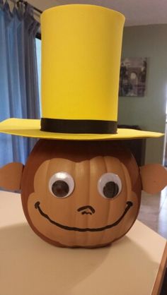 a monkey head with a yellow top hat on it's head, sitting on a table