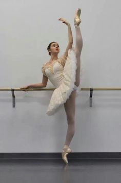 a ballerina in white is leaning on the wall