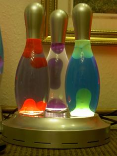 three colorful vases sitting on top of a table next to a mirror in a room