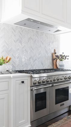 a stove top oven sitting inside of a kitchen next to white cabinets and counter tops