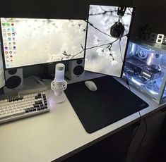 two computer monitors sitting on top of a desk next to a keyboard and mouse pad