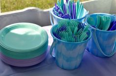 three cups with toothbrushes in them sitting on a table next to plates and bowls