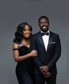 a man in a tuxedo standing next to a woman wearing a black dress