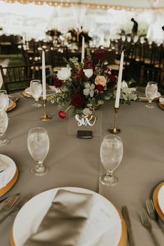 the table is set with silver and gold plates, place settings, and candles for an elegant wedding reception