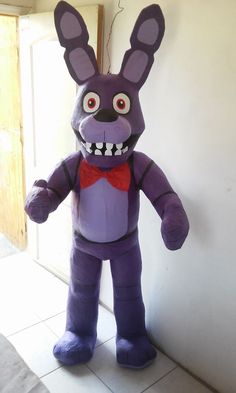 an inflatable purple bunny standing next to a wall