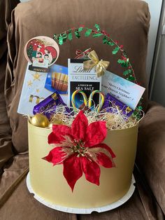 a christmas gift basket sitting on top of a brown couch next to a chair with a red poinsetti