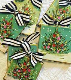 four decorated christmas cookies with black and white ribbons on them, sitting next to each other