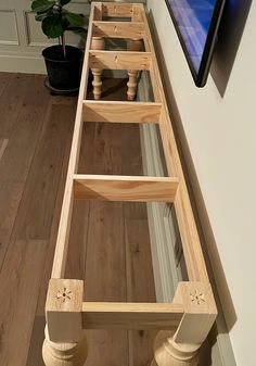 a wooden bed frame sitting on top of a hard wood floor next to a potted plant