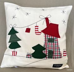 a white pillow with christmas trees and presents hanging from the line on it's side