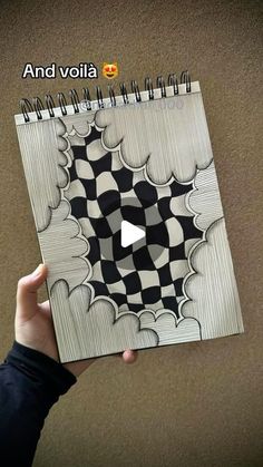 someone is holding up a spiral notebook with an image of a black and white checkered pattern