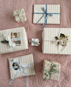 four wrapped presents sitting on top of a bed next to each other with ribbons and bows