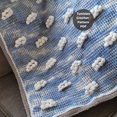 a crocheted afghan with sheeps on it is sitting on a couch next to a pillow