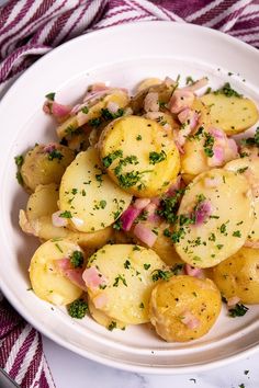 a white bowl filled with potatoes covered in parsley